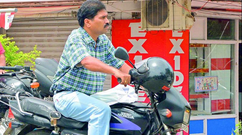 A two-wheeler rider hangs his helmet from his motorcycle, a popular practice. (Photo: DC)