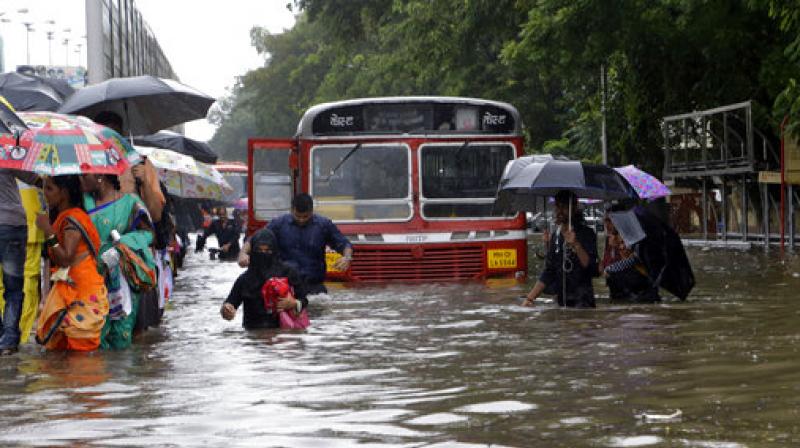 People walk through a waterlogged street following heavy rains in Mumbai. (Photo: AP)