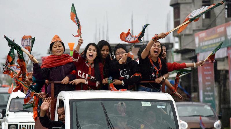 Supporters of BJP wave their flags as they celebrate their candidate win Assembly elections in Imphal. (Photo: PTI)