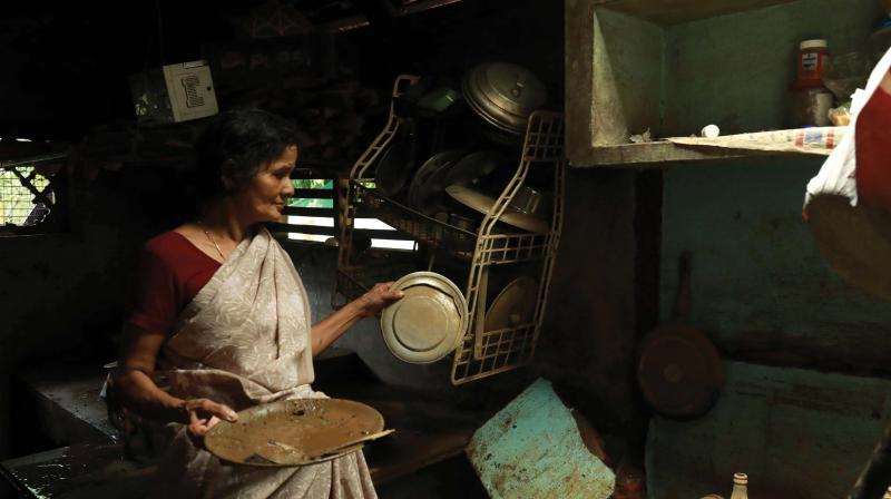 A woman at Cheripallathurthu near Paravur examines what materials she could salvage from her kitchen devastated during the floods.
