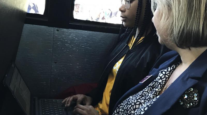 St. Stephen Middle School student Lakaysha Governor works on her Chromebook on Monday, March 20, 2017, on a school bus recently outfitted with WiFi by tech giant Google, as College of Charleston professor RoxAnn Stalvey looks on in St. Stephen, S.C. Lakysha is one of nearly 2,000 students in South Carolinas rural Berkeley County benefiting from a grant from Google, which on Monday unveiled one of its WiFi-equipped school buses in the area. (AP Photo/Meg Kinnard)