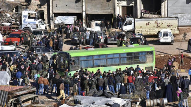 Residents gather near a green government bus for evacuating from eastern Aleppo, Syria on Thursday. (Photo: AP)