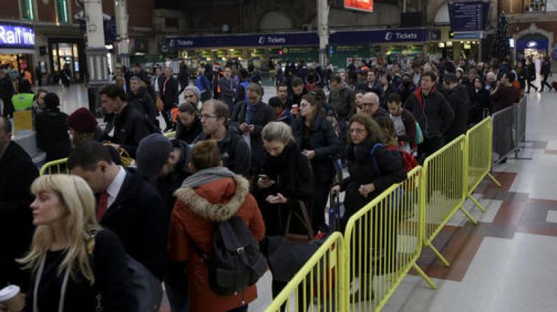 Passengers queue up for an express train to Gatwick Airport, running a reduced service as a result of a train strike, in Victoria rail station London. (Photo: AP)