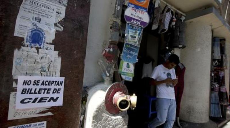 Customer who tried to make a purchase with 100-bolivar notes leaves a shop with a message posted in Spanish, not accepting the 100 bank note, in Caracas, Venezuela. (Photo: AP)