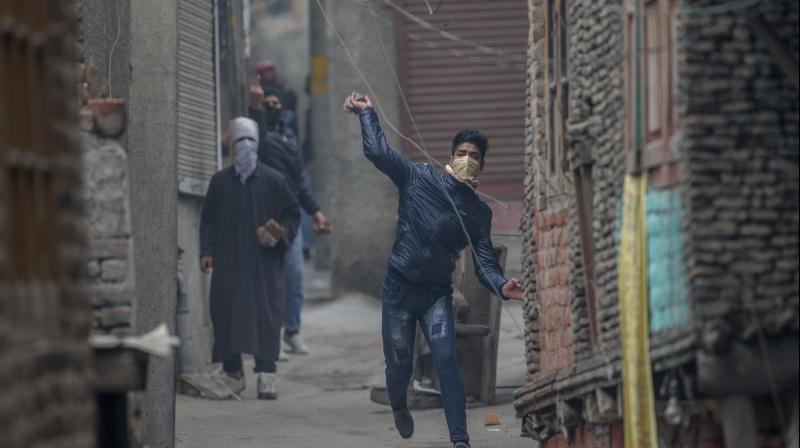 A protester throws stones at policemen during a protest near the Jamia Masjid, Srinagar. (Photo: AP)