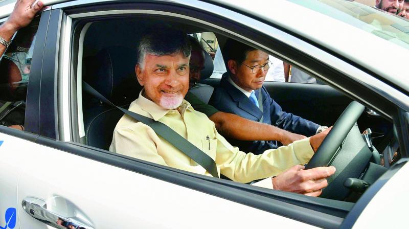 Chief Minister N. Chandrababu Naidu tries his hand at the wheel of a Kia Motors eco-friendly vehicle in Vijayawada on Thursday. (Photo: DC)