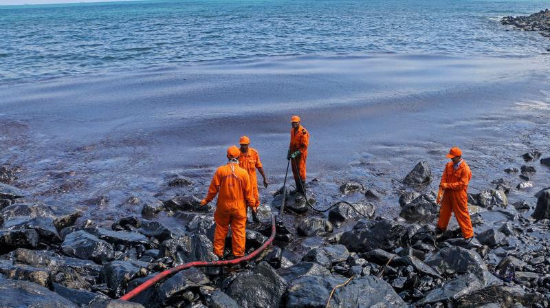 Members of the Pollution Response Team removing black oil washed ashore as a thick oily tide from the sea lapped at the coast, a day after an oil tanker and an LPG tanker collided near Kamarajar Port in Ennore in Chennai. (Photo: PTI)