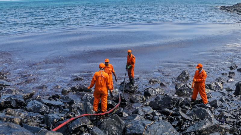 Members of the Pollution Response Team removing black oil washed ashore as a thick oily tide from the sea lapped at the coast, days after an oil tanker and an LPG tanker collided near Kamarajar Port in Ennore in Chennai. (Photo: PTI)