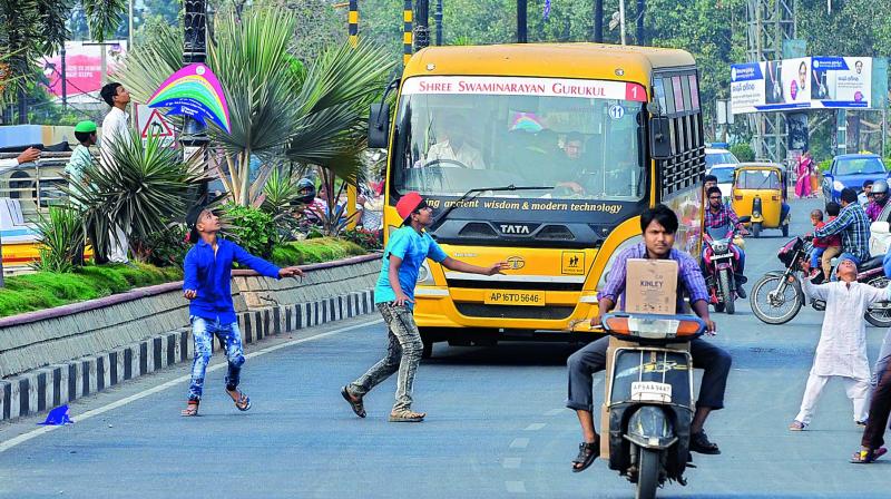 Children run after kites risking their lives in the heavy traffic near Peoples Plaza in the city on Friday. (Photo: DC)