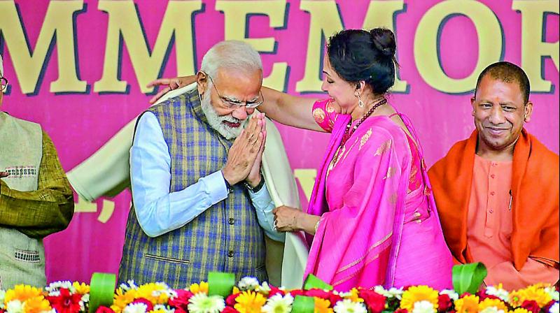 PM Narendra Modi being greeted with a shawl by the local BJP MP Hema Malini as CM Yogi Adityanath looks on in Vrindavan near Mathura, Monday. (PTI)