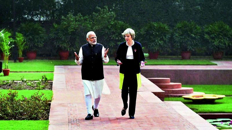 Prime Minister Narendra Modi walks with his UK counterpart Theresa May in lawns of Hyderabad House before a meeting in New Delhi on Monday. (Photo: PTI)