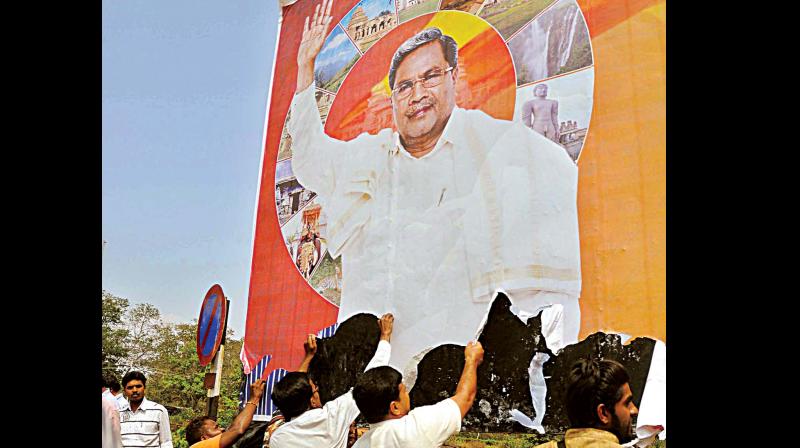 BJP workers, who were protesting against the State governments decision to celebrate Tipu Jayanti, tearing a huge poster of Chief Minister Siddaramaiah in Mysuru on Monday (Photo: KPN)
