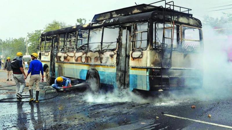 Firefighters and policemen try to douse a fire after activists of the Karni Sena torched a Haryana Roadways bus during a demonstration against the release of Padmaavat in Gurgaon. (Photo: PTI)