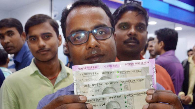 A man shows Rs 500 and Rs 2000 notes after withdrawing from an ATM in Patna. (Photo: PTI)