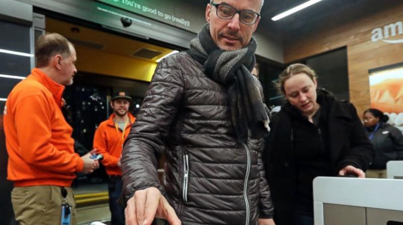 A customer scans his Amazon Go cellphone app at the entrance as he heads into an Amazon Go store in Seattle. One firm building automated checkout systems, AVA Retail, said Thursday, June 14 that it is working with Microsoft on the technology for physical stores. (AP Photo/Elaine Thompson, File)