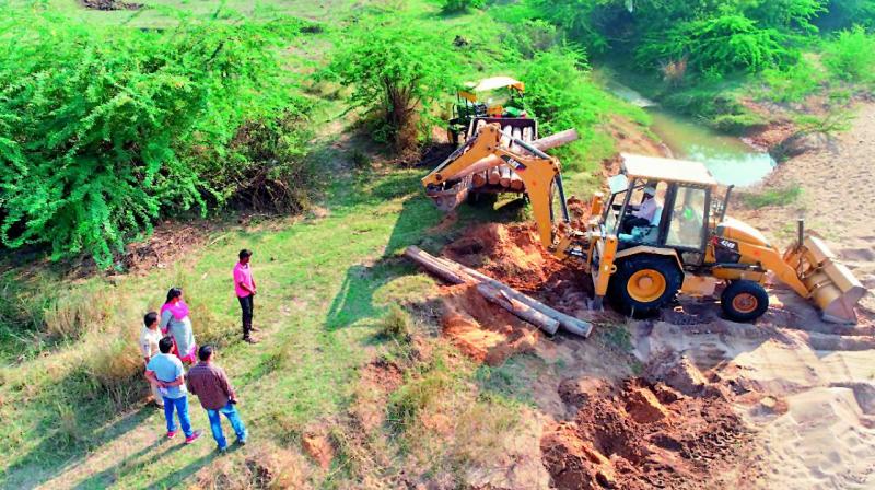The police unearth the teak logs from the sand on the shore of the river Godavari in Manthani in Peddapalli district. (Photo:DC)