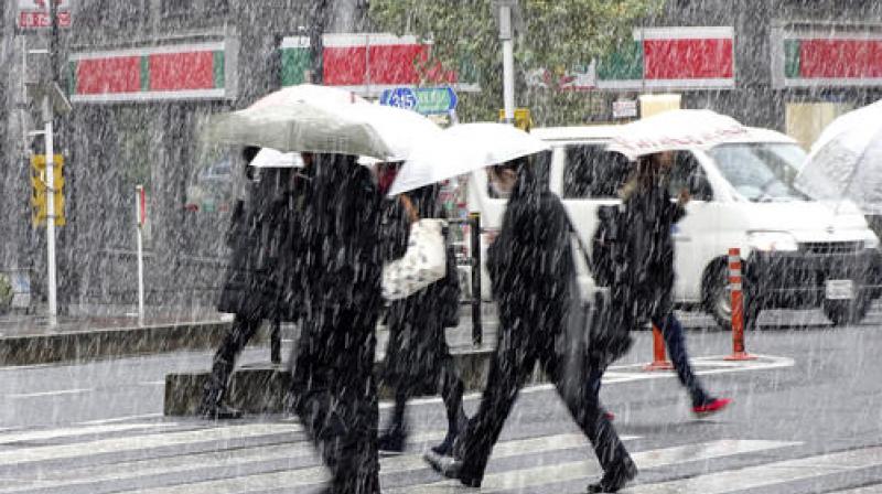 Pedestrians cross a street in the snow in Tokyo. (Photo: AP)