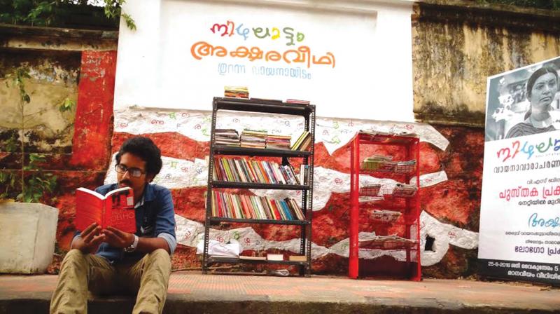 A youngster reading books at Nizhalattom Aksharaveedhi, the open library at Manaveeyam Veedhi in Thiruvananthapuram on Tuesday.	(Photo: DC)
