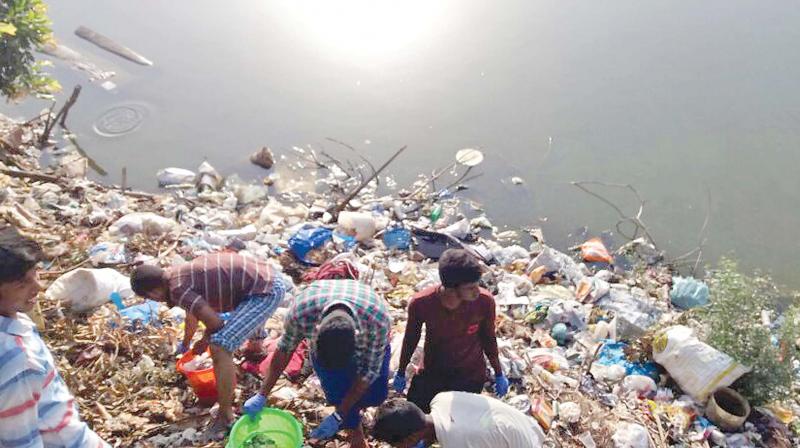 People clean the garbage filled Vadakkupattu lake.