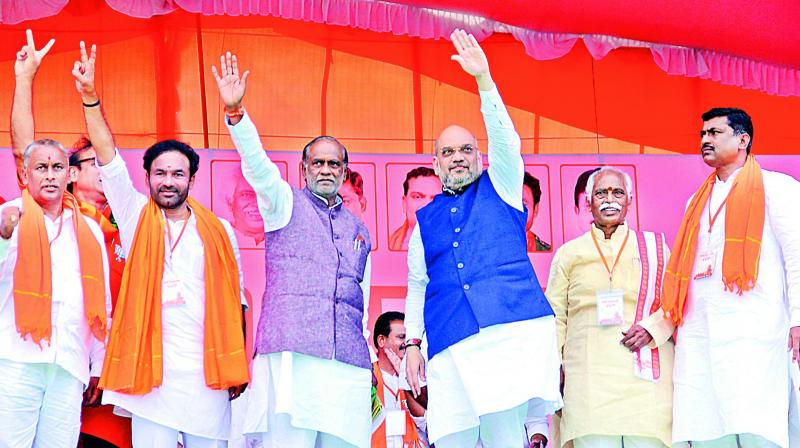 BJP national president Amit Shah (right) waves to the massive crowd along with BJP state president K. Laxman (left) during a poll campaign at Mahbubnagar on Saturday.  (Photo: Pavan)