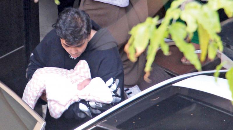 Karan Johar steps out of the hospital with one of the twins.
