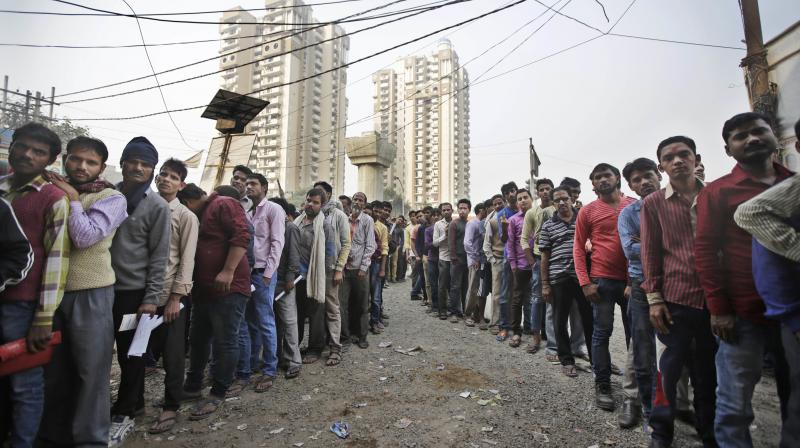 People stand in lines outside a bank to exchange or deposit discontinued currency notes in New Delhi. (Photo: AP)