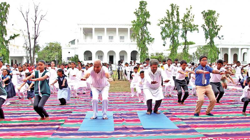 Governor Banwarilal Purohit performs yoga at the 4th International Yoga Day event held at Raj Bhavan along with employees and students, on Thursday. (Photo: DC)