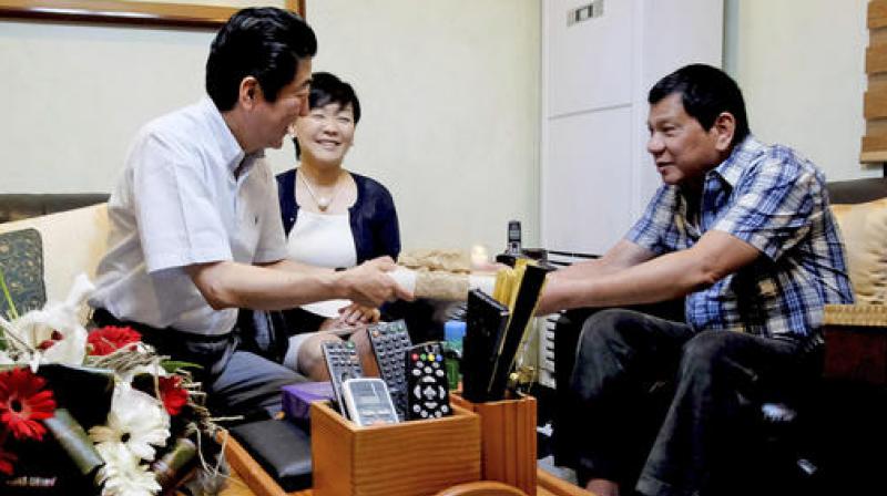 Philippine President Rodrigo Duterte, hands a gift to visiting Japanese Prime Minister Shinzo Abe and his wife Akie to the Presidents residence at Dona Luisa Village in Davao City. (Photo: AP)