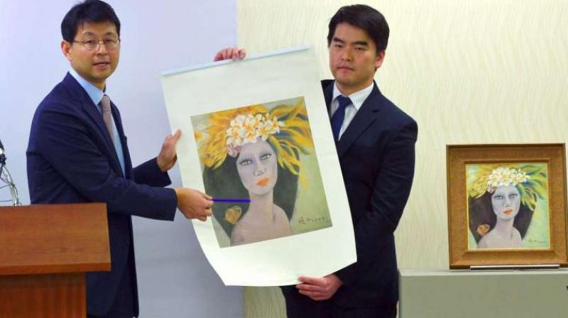 Members of the prosecutors team holding up a copy of the painting Beautiful Woman on Dec 19, 2016. (Photo: AFP)