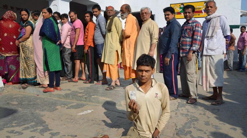 A physically challenged person shows his voter identity card as others wait to cast votes at a polling station during the final phase of Assembly polls in Mirzapur. (Photo: PTI)