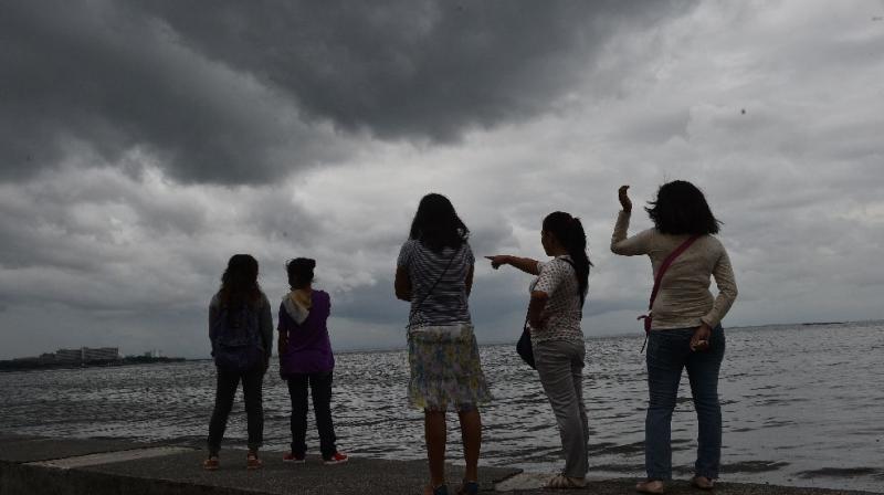 People watch as storm clouds gather around Manila Bay on October 16, 2016, after Typhoon Sarika passed north of the capital overnight. (Photo: AFP)