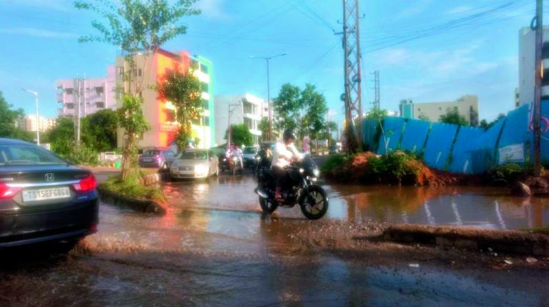 Motorists plough through a giant crater formed on the Nallagandla road due to rains and drainage overflowing from the nearby colony and restaurant.  (Photo: DC)