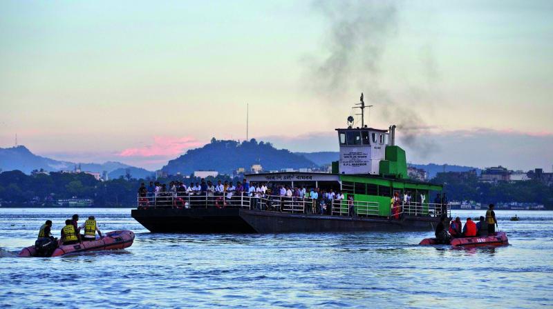 A passenger ferry crosses as rescuers search in the Brahmaputra River after a boat capsized. 	AP