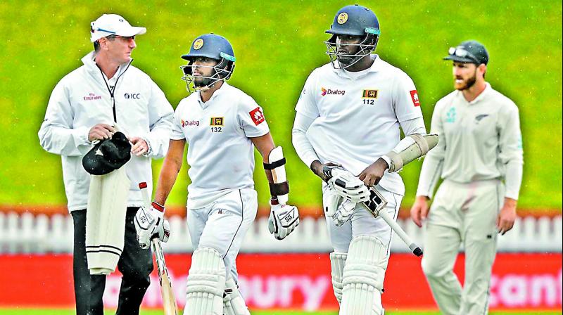 Sri Lanka batsmen Kusal Mendis and Angelo Mathews walk off the field as rain stops play. 	 AP